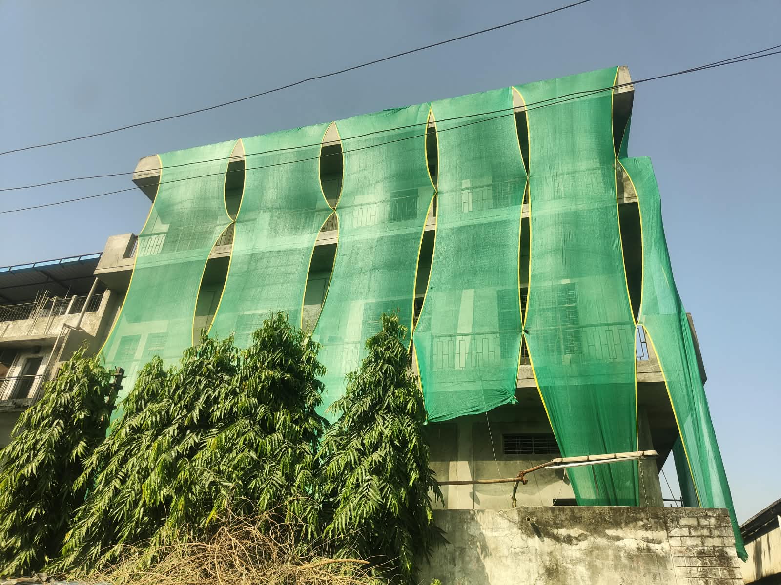 Kundli building in Haryana with green-net dust-control covering — HSPCB construction site